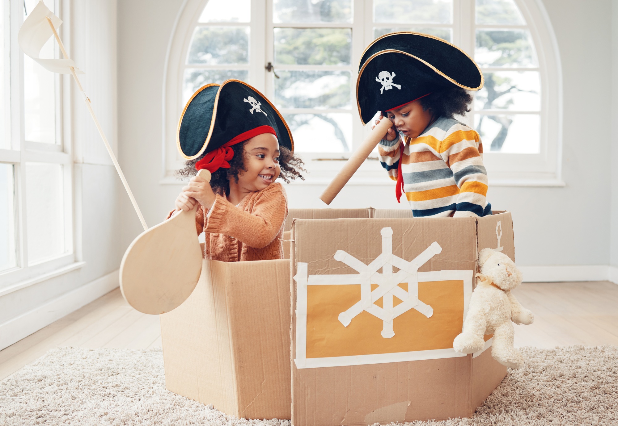 Playing, box ship and pirate kids role play, fantasy imagine or pretend as yacht captain in cardboa